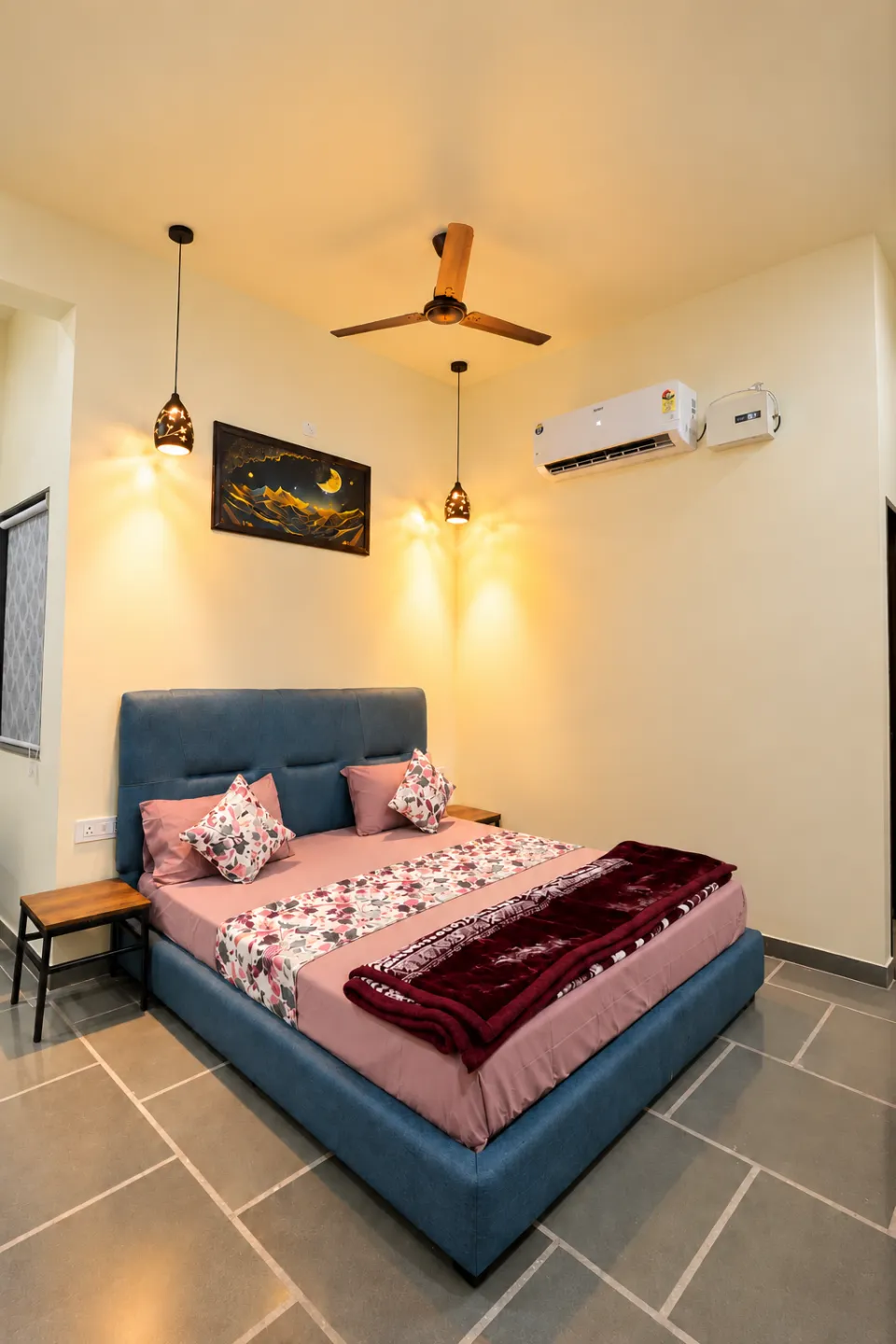 Cozy teal bedroom in a udaipur villa with pink floral bedding, warm pendant lights, wooden accents, and elegant decor
