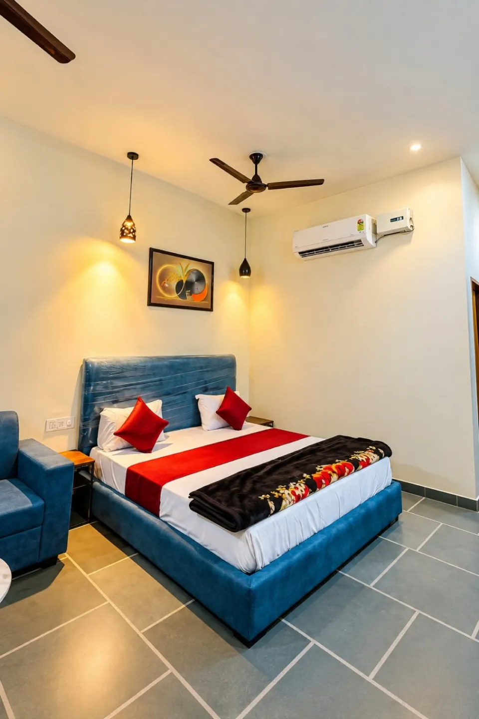 Udaipur Deluxe Villa Room with a plush blue bed, red accents, pendant lights, ceiling fan, AC, and tiled floor area